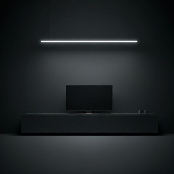 A minimalist living room with a dark wall and a flat-screen TV mounted above a media console. A long, linear LED light is mounted on the wall above the TV, providing ambient lighting.