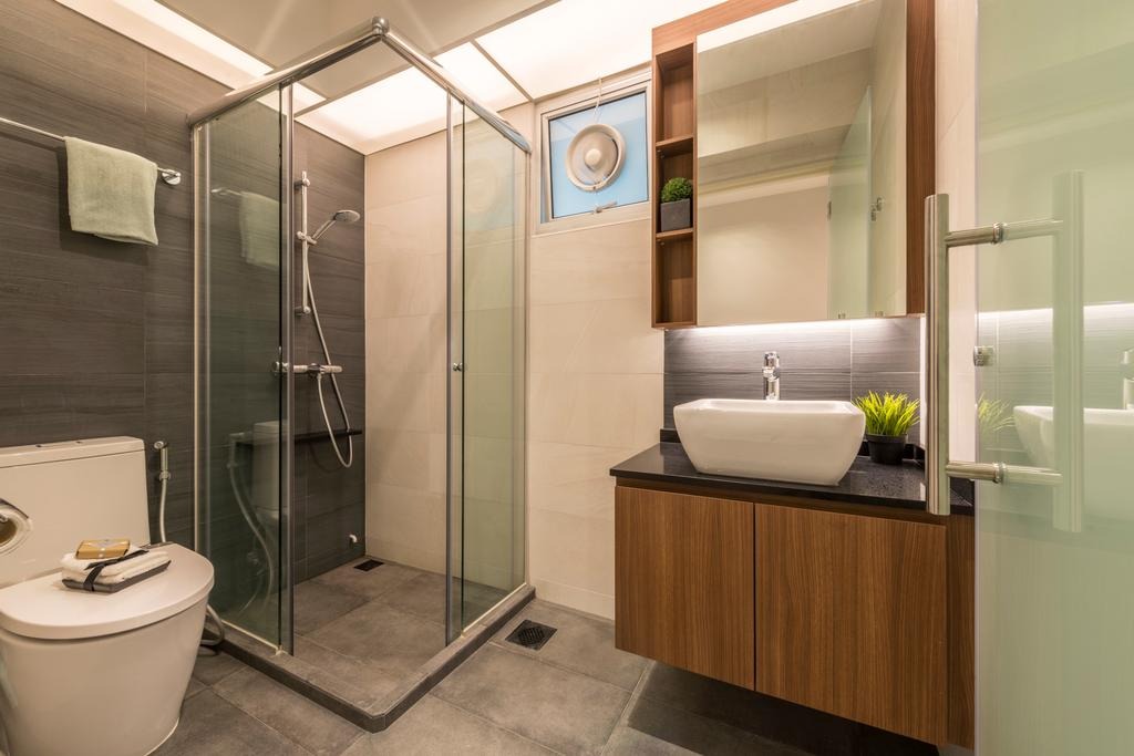 A modern bathroom with a walk-in shower, a vanity with a white sink and wooden cabinets, and a toilet. The room has a sleek and contemporary design with clean lines and neutral colors.