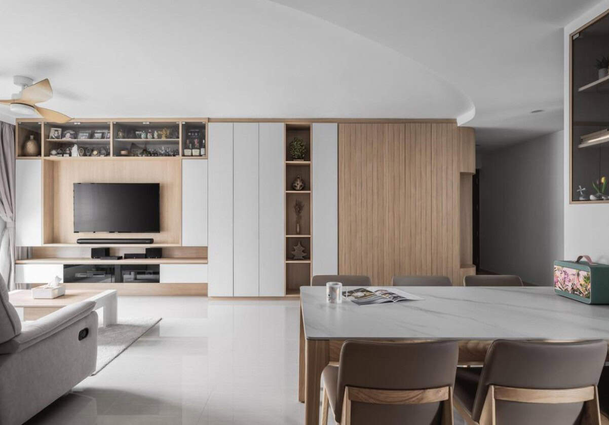 A modern open-concept living and dining area with a minimalist design. The space features a comfortable sofa, a dining table with chairs, and built-in shelves and cabinets. The overall aesthetic is clean and contemporary.