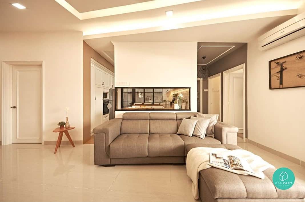 An open-concept living room with a comfortable L-shaped sofa and a side table. The room features a neutral color palette and plenty of natural light.