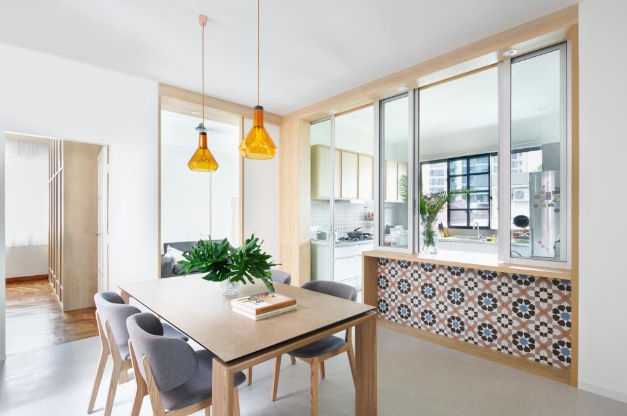 A modern dining room with a wooden dining table and chairs. Two colorful pendant lights hang above the table, adding a pop of color to the space. The room features a minimalist design with clean lines and neutral colors.